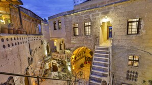 A historic building with a courtyard, stone walls, and a staircase leading to an upper level. - Kookaburra Hotel (Nevsehir)