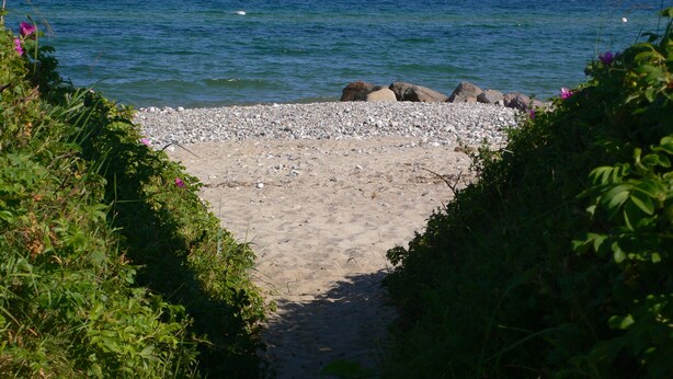 A pathway leading to a rocky beach with a view of the sea and distant wind turbines. - Vacation on the manor - small cozy apartment near the Baltic Sea (Waabs)