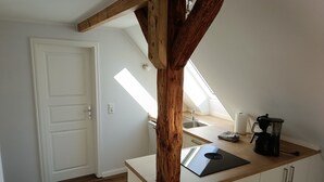 A kitchen with a wooden beam ceiling, a laptop on the counter, a coffee maker, and a view of the adjacent room. - Vacation on the manor - small cozy apartment near the Baltic Sea (Waabs)