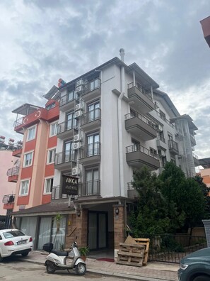 A multi-story hotel with balconies, air conditioning units, and a sign indicating it is an apartment hotel.