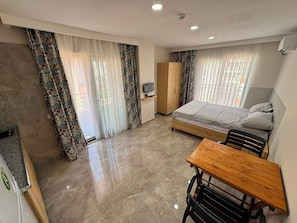 A hotel room with a bed, a wooden desk, a wardrobe, and a television. - Akca Apart Otel (Antalya)