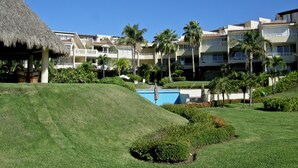 Ein Resort mit Pool, Palmen und einem Gebäude mit Reetdach.