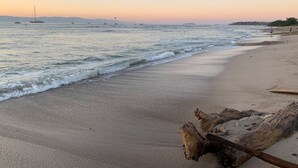 Ein Strand mit ruhigen Wellen und einem Treibholzstamm im Sand.