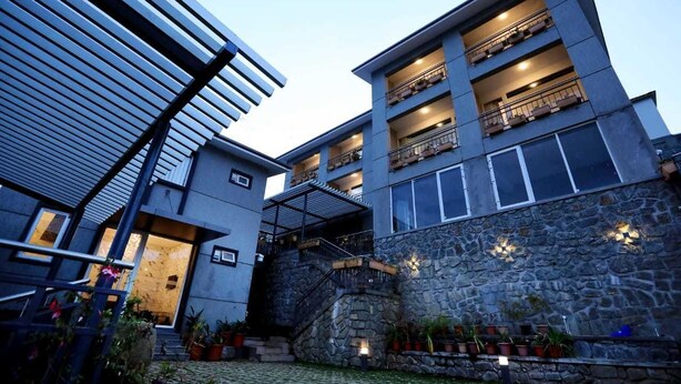 A multi-story building with balconies, a stone facade, and a staircase leading to the entrance. - Cherry Blossom Homestay (Kodaikanal)