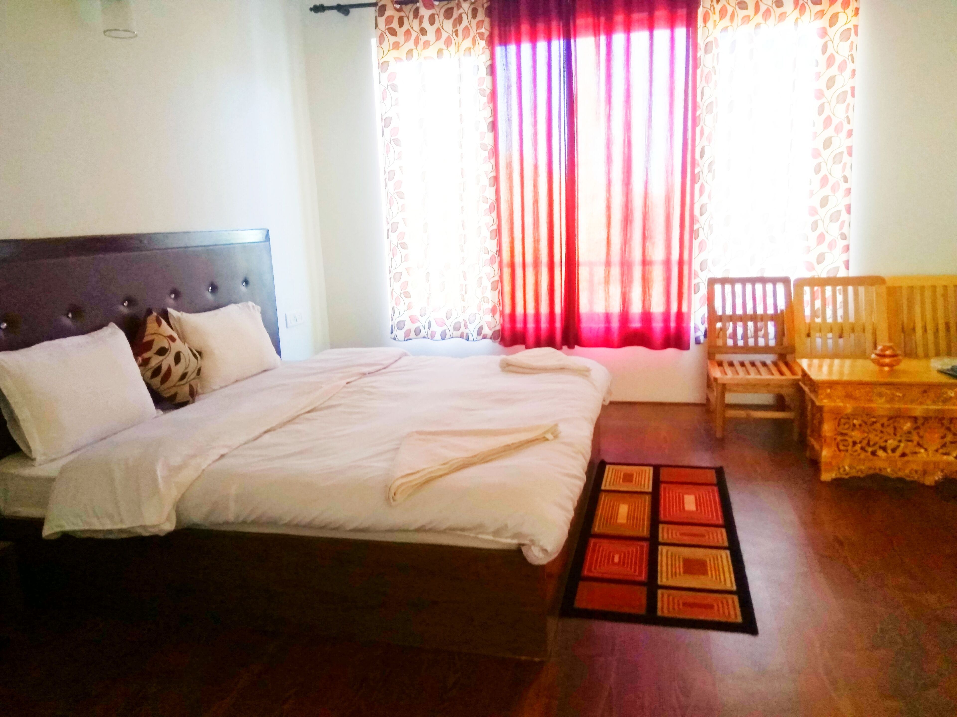 Quarto com cama, um banco de madeira e uma mesa.