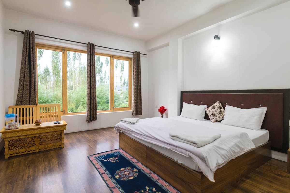 Quarto com cama grande, cabeceira de madeira e mesa de cabeceira com abajur.