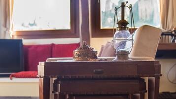 A wooden table with a lamp and a decorative item on it, positioned in front of a window with curtains.
