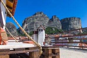 A coastal terrace with a rope barrier, a small white tower, and rocky cliffs in the background. - Tasos House_Panoramic View  (Kalabaka)