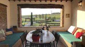 Eine Terrasse mit einem runden Tisch, Stühlen und Blick auf einen Weinberg.