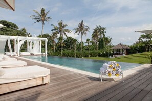 A poolside area with lounge chairs, a gazebo, and a neatly arranged stack of towels. - Wholesome Luxury 7BR Villa, Canggu - w/ Spacious Pool & Lounging Area! (Canggu)