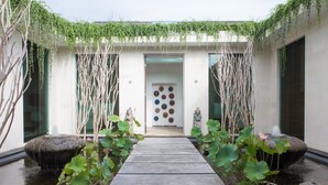 Un sendero tranquilo que lleva a un edificio con una puerta decorativa, rodeado de fuentes de agua y vegetación.