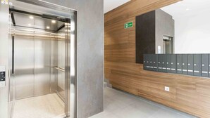 An elevator with a metallic interior, a wooden reception desk, and a wall-mounted mailbox. - Seattle | The Rentals Collection (San Sebastián)