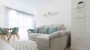 A modern living room with a sofa, chairs, and a dining table. - Seattle | The Rentals Collection (San Sebastián)