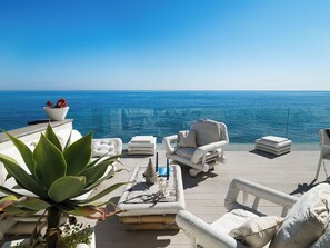 A deck with white outdoor furniture, a potted plant, and a view of the ocean. - Unique Apartment with Panoramic Terrace and Hammam (Aci Castello)