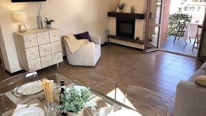 Ein modernes Wohnzimmer mit Kamin, einem Essbereich mit Glastisch und einer Couch.