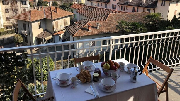 Ein Balkon mit Frühstückstisch, mit Blick auf eine Stadt mit historischen Gebäuden und einem Berg im Hintergrund.