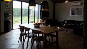 Un área de comedor con una mesa y sillas de madera, un ventanal con vistas al exterior y lámparas colgantes.