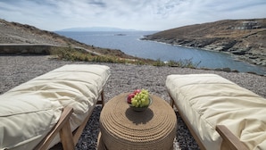 A seaside view with two lounge chairs facing a rocky coastline and a body of water. - Simousi Villas (Kithnos)