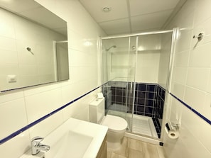 A bathroom with a shower, toilet, and sink.