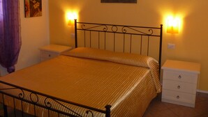 A bed with a headboard, two bedside tables, and a wall-mounted lamp. - SHORT TERM LET IN SARDINIA, HOLIDAY HOME OLBIA-PITTULONGU WITHIN 5MIN FROM BEACH (Olbia)