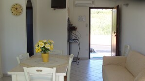 A dining area with a table, chairs, a clock, and a vase of flowers. - SHORT TERM LET IN SARDINIA, HOLIDAY HOME OLBIA-PITTULONGU WITHIN 5MIN FROM BEACH (Olbia)