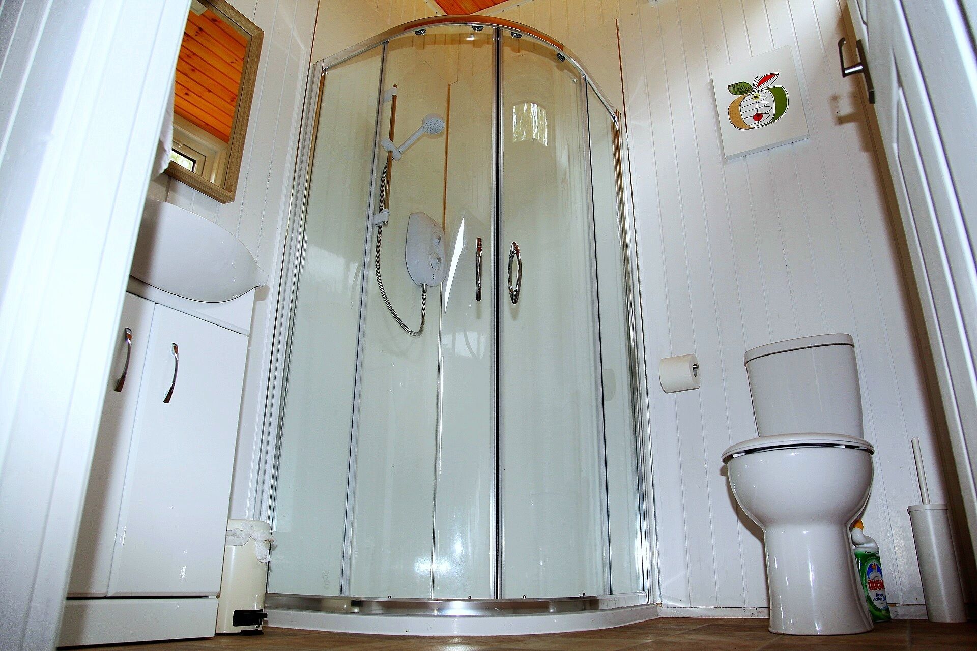 Un baño con cabina de ducha, inodoro y un mueble pequeño.