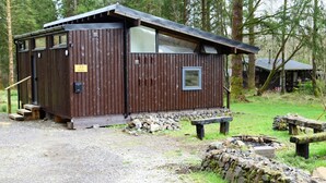 A rustic cabin with a wooden exterior, a small window, and a door. - SKERRY is an authentic log cabin in a lovely forest location close to Loch Awe (Taynuilt)