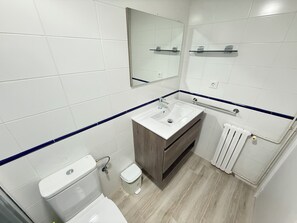 A modern bathroom with a toilet, sink, mirror, and radiator.