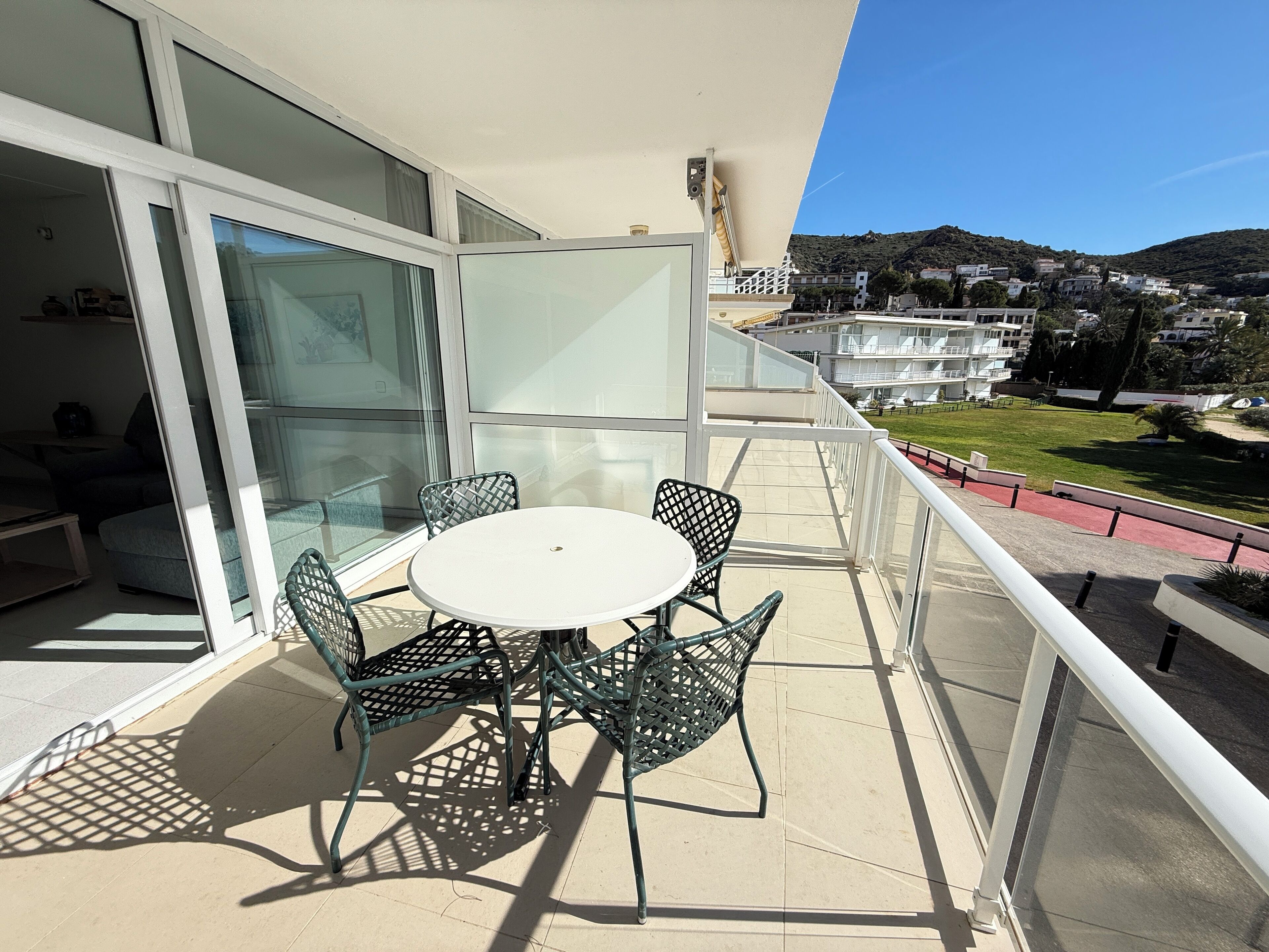 A balcony with a glass door, a round table, and four chairs.
