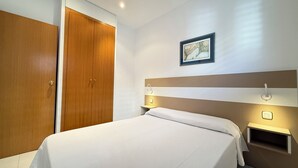 Ein Hotelzimmer mit Bett, Schrank, Nachttisch und einer Wandablage.