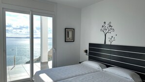 A bedroom with a bed, a framed picture, and a wall art of a tree. - Agi Joan Margarit 84B Casa for rent in Roses Girona. (Rosas / Roses)