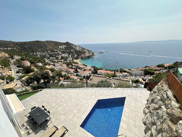 Zona residencial con piscina, vista al mar y una colina con edificios.