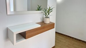 Uma casa de banho moderna com uma toucador branca, um espelho e uma planta em vaso.
