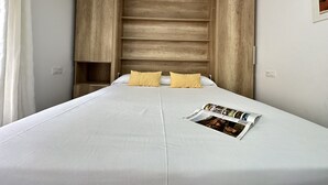 A bedroom with a large bed, wooden headboard, and a magazine on the bed. - Agi Arago 152 Apartamento for rent in Roses Girona. (Rosas / Roses)