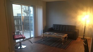A living room with a dark-colored sofa, a coffee table, a red chair, and a floor lamp.
