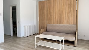A modern living room with a wooden wardrobe, a beige sofa, and a white coffee table.