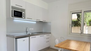 A compact kitchen with a microwave, sink, and a wooden table with chairs. - Agi Rescator 122 Apartamento for rent in Roses Girona. (Rosas / Roses)