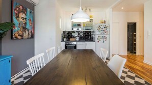 A modern kitchen with white cabinets, a black countertop, and a hanging pendant light. - Amazing design, Huge, Prime location, With Parking (Stari Grad)
