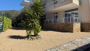 A multi-story building with balconies, a gravel driveway, and a stone wall. - Agi Rescator 104 Apartamento for rent in Roses Girona. (Rosas / Roses)