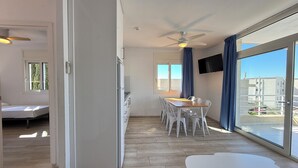 Un appartement moderne comprenant un coin repas, un lit, une cuisine et de grandes fenêtres offrant une vue sur la ville.