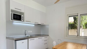 Eine kleine Küche mit einer Mikrowelle, einem Spülbecken und einem Holztisch mit Stühlen.