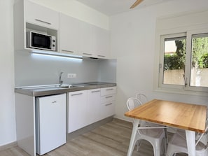 A compact kitchen with a microwave, sink, and a wooden table with chairs.
