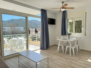 A balcony with a table and chairs, a ceiling fan, and a TV mounted on the wall. - Agi Rescator 105 Apartamento for rent in Roses Girona. (Rosas / Roses)