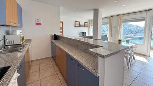 Une cuisine moderne dotée de plans de travail en granit, d’un four à micro-ondes encastré et d’un évier.