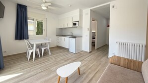 Een moderne keuken met witte kastjes, een magnetron en een eethoek met een witte tafel en stoelen.