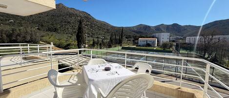 Una terraza con una mesa preparada para dos, con vistas a un paisaje montañoso.