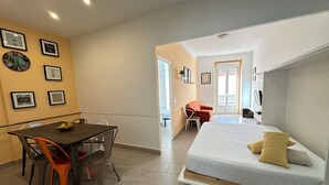 A compact room with a bed, a dining table with chairs, and a small seating area with a chair. - Agi Joan Badosa 1A Apartamento for rent in Roses Girona. (Rosas / Roses)