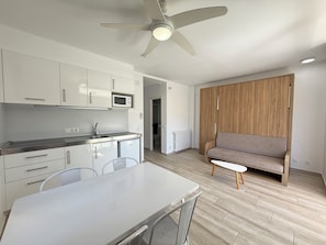 A modern kitchen with white cabinets, a microwave, and a ceiling fan.