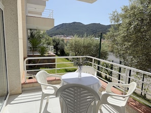 A balcony with a table and chairs, overlooking a mountainous landscape.