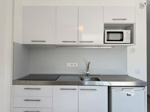 A modern kitchen with white cabinets, a stainless steel sink, a microwave, and a dishwasher.